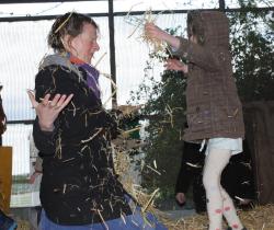 IImage of a child throwing hay over a smiling adult