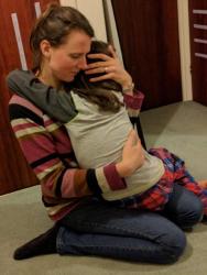 Image of a dark-haired woman embracing a child who is sat on her lap